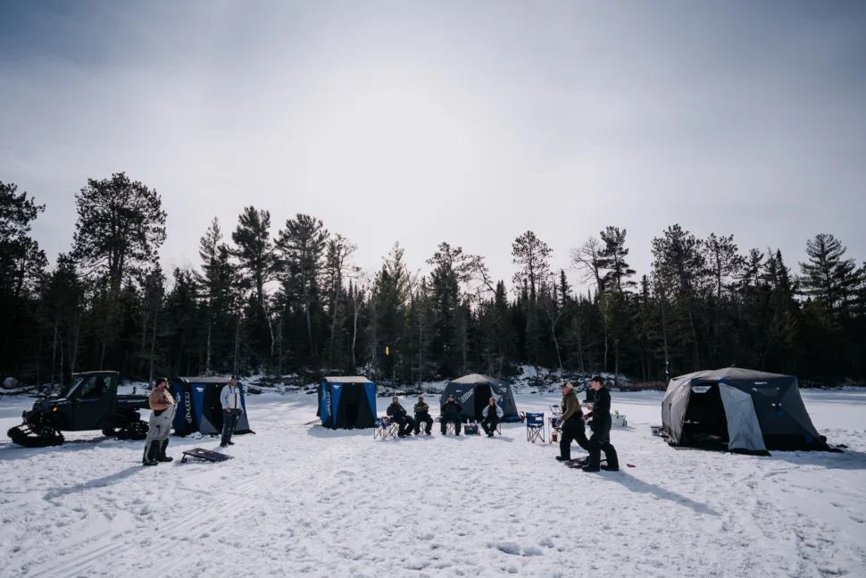 Ice fishing camp with multiple Otter shelters on a frozen lake.